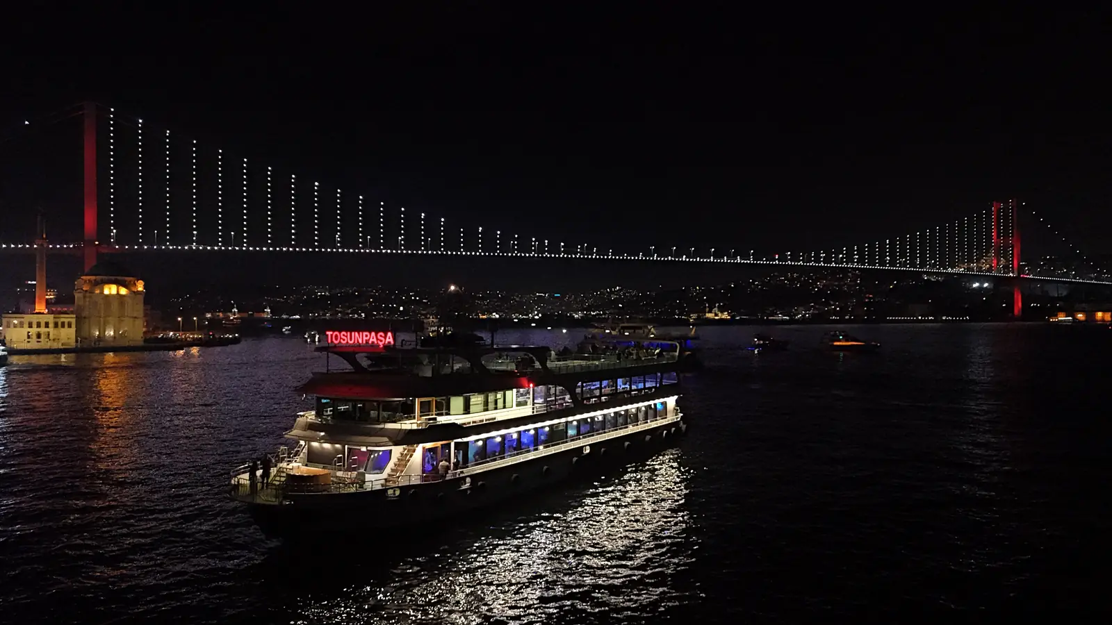 Our dinner cruise boat sailing under the lit-up Bosphorus Bridge at night